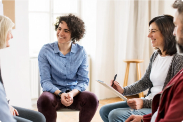 Addiction Treatment: People smiling and interacting during group therapy session