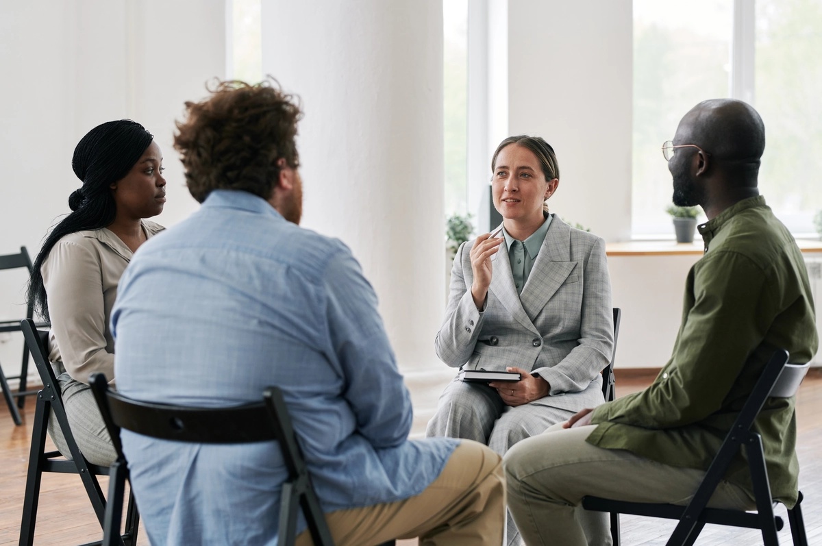 A group therapy session with people sitting in chairs, a core component of outpatient rehab.