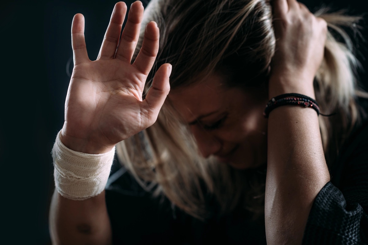 A woman with a bandaged wrist holds her hand to the camera.