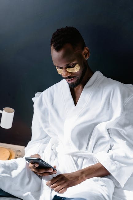 PIcture of a man in bed in a robe, practicing self-care.