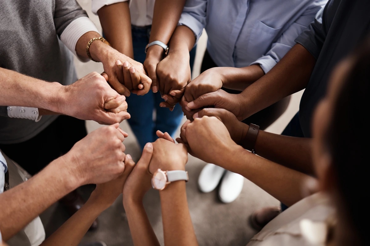 Multiple hands joining together in group therapy.