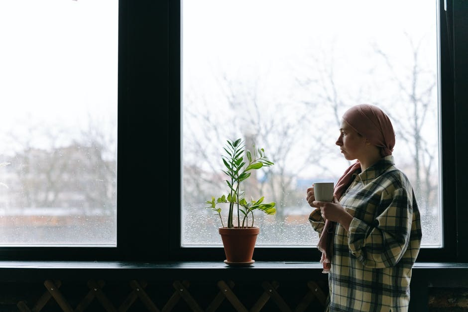 A woman standing by the window holding a mug.