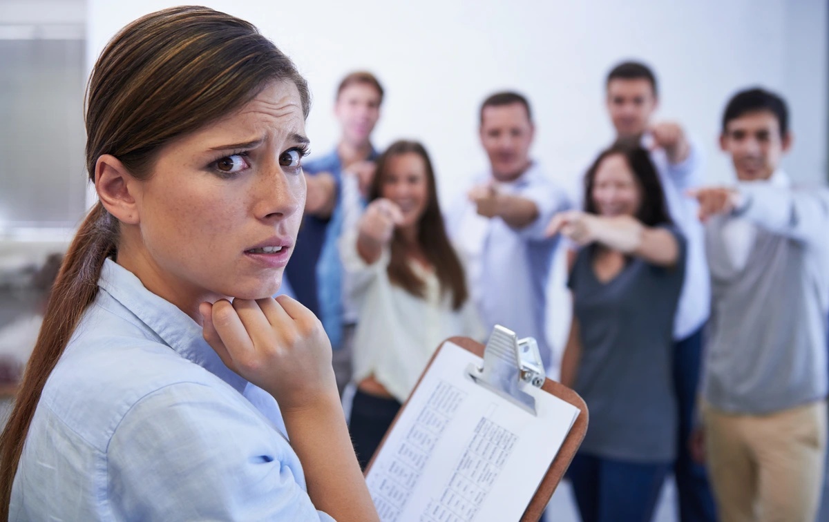 A woman feeling as if her coworkers are laughing at her, possibly suffering from social anxiety disorder.