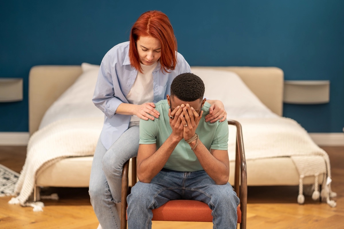 A man being comforted by his partner as he struggles with persistent depressive disorder.