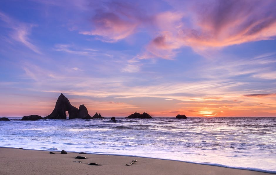 Photograph of a rocky beach at sunset. It's peaceful, which is the state holistic treatments aim to create.