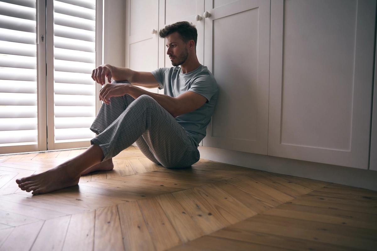 A man sitting against either a closet or a pantry.