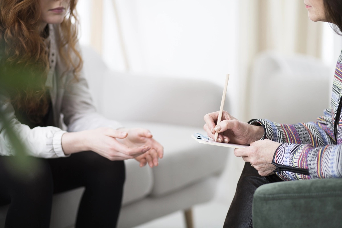 A woman talks to a therapist while the therapist takes notes.