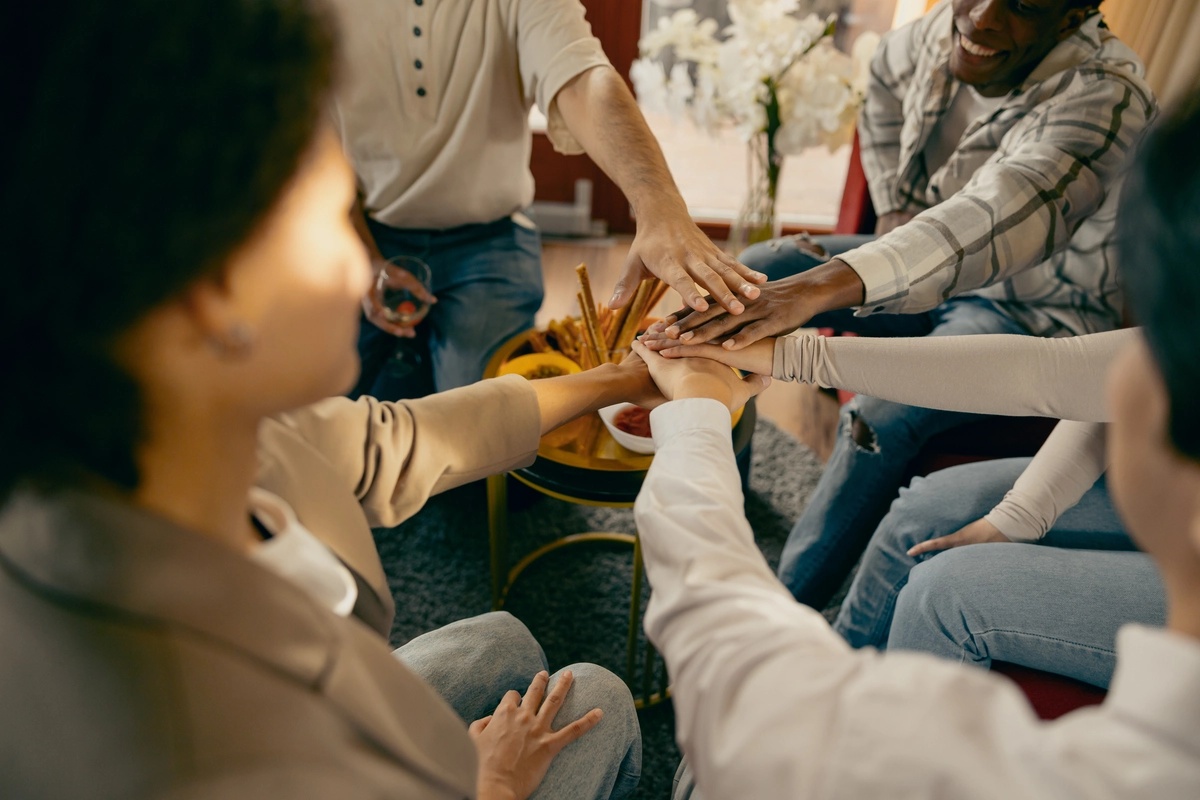 A group of people in outpatient rehab sitting in a circle and joining hands.