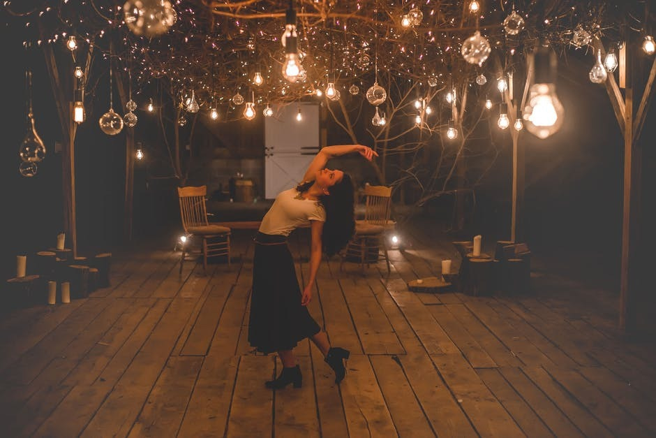 A woman dancing under electric lights.
