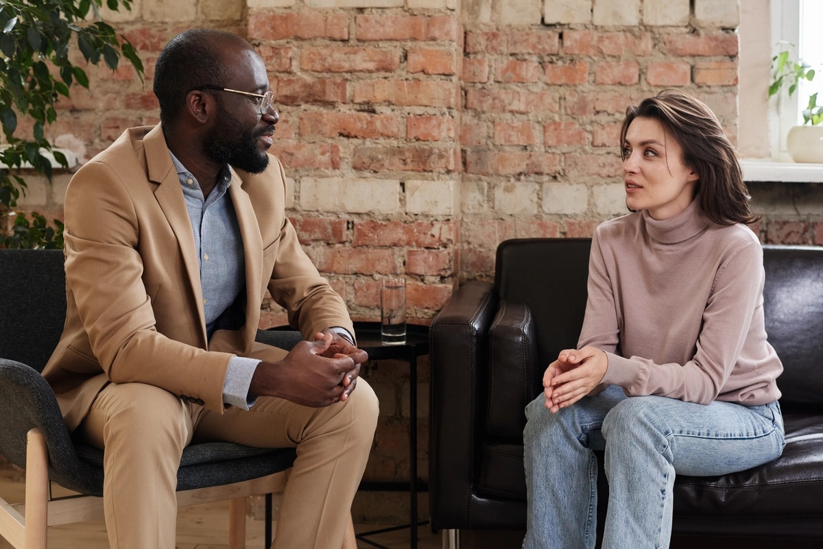 A therapist talks with his patient on a couch.