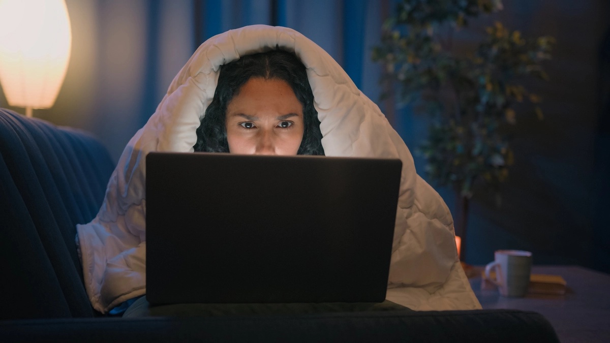 A woman staying up late on her laptop and suffering from internet addiction.