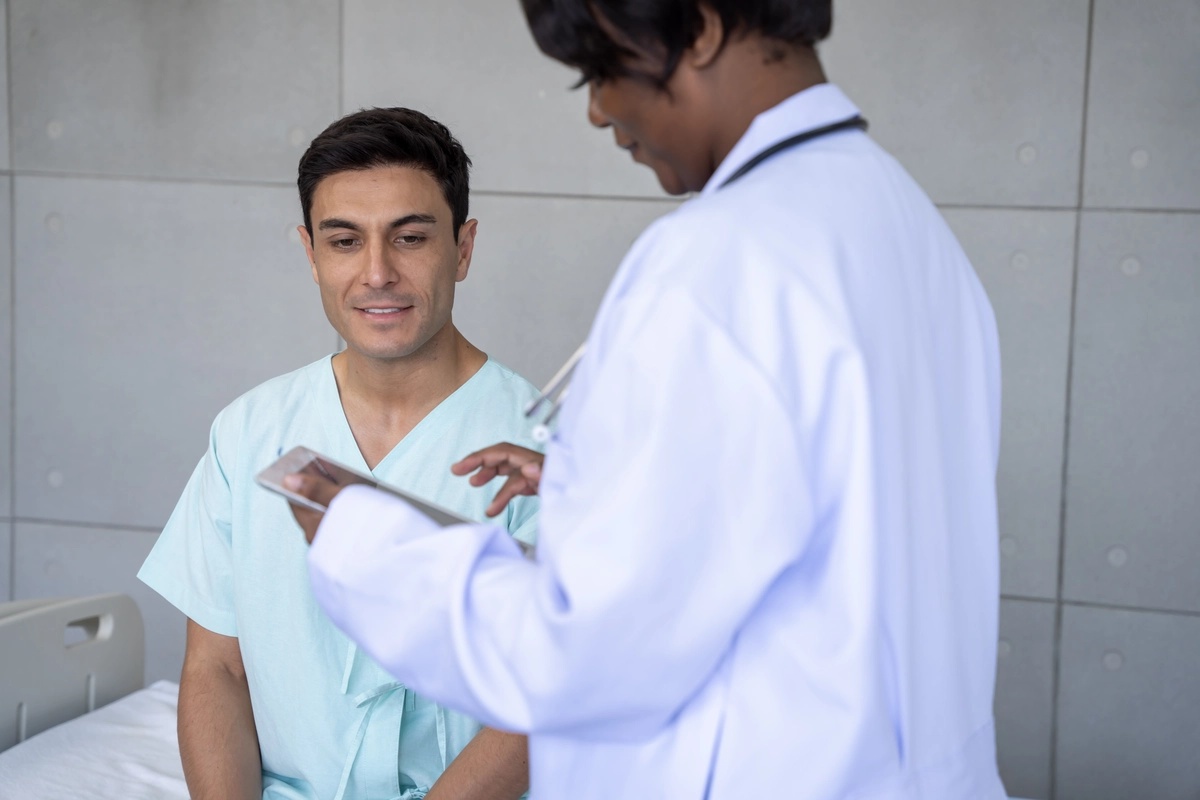 A man smiling after going through detox, as his doctor reads from a clipboard.