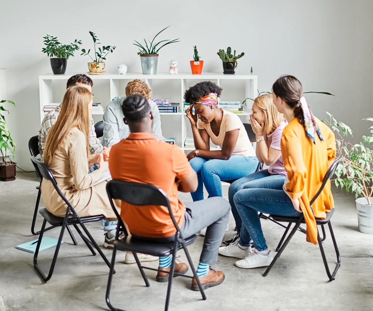 An alumni support group sitting in a circle and laughing with each other.