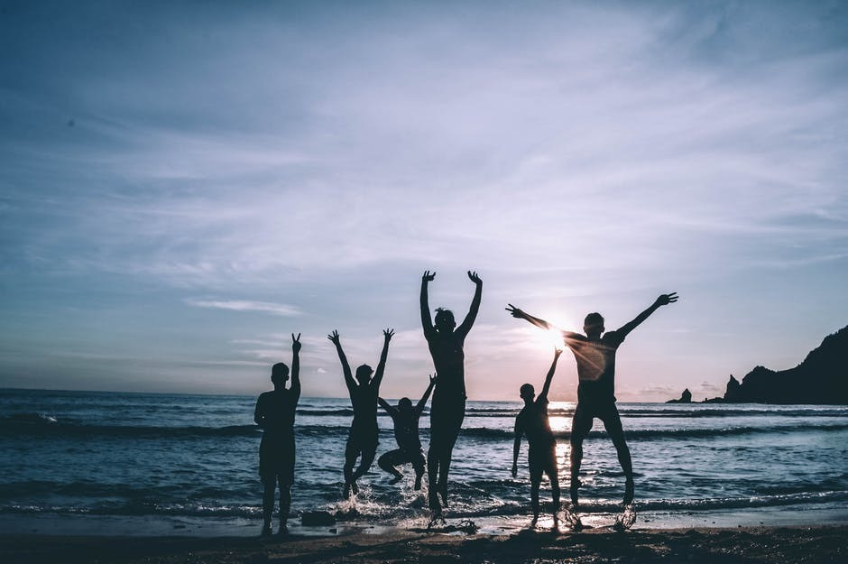 Photo of happy people at the beach during sunset.