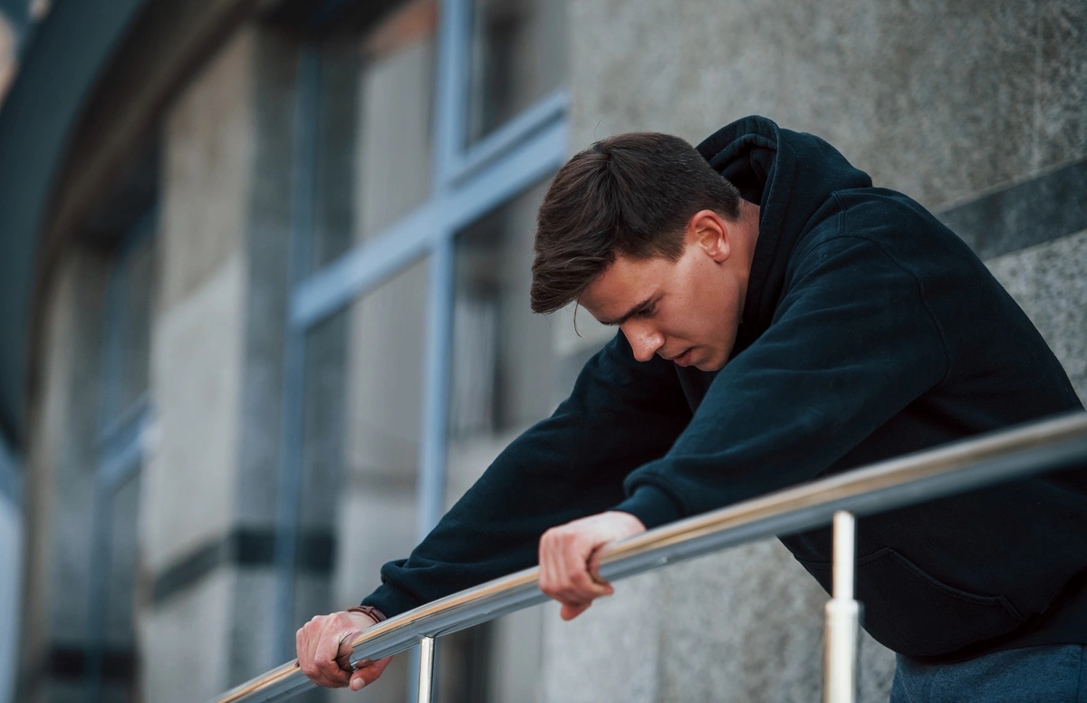 Man needs crisis stabilization on the verge of jumping, gripping a railing.