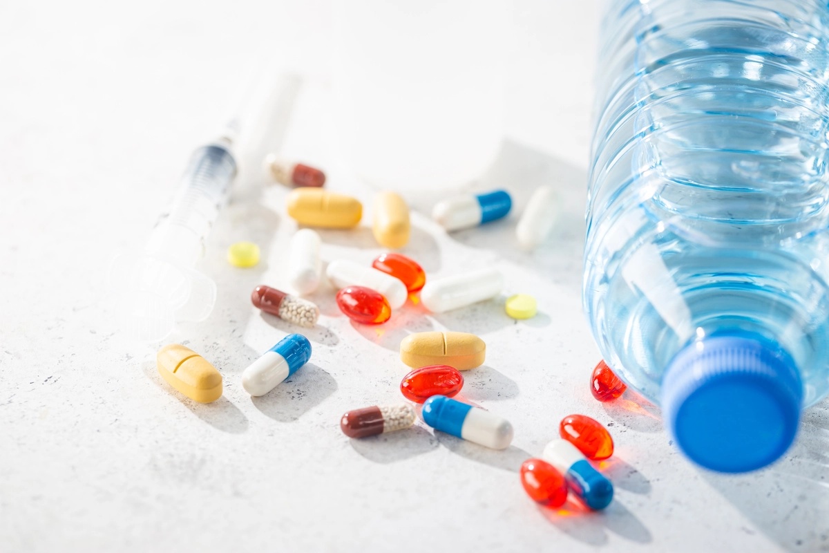 A bunch of pills next to a bottle of water to be used in medical detox.