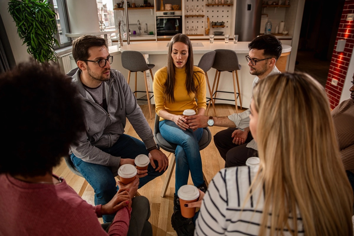 A group of people sitting in a circle and drinking coffee, possibly a panic disorder support group incorporating self-help strategies.