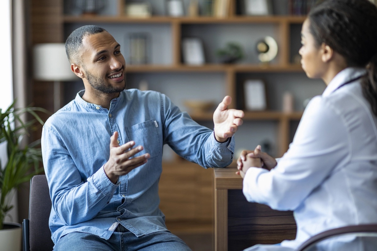 A man smiles as he speaks to a physician and discusses detox options.