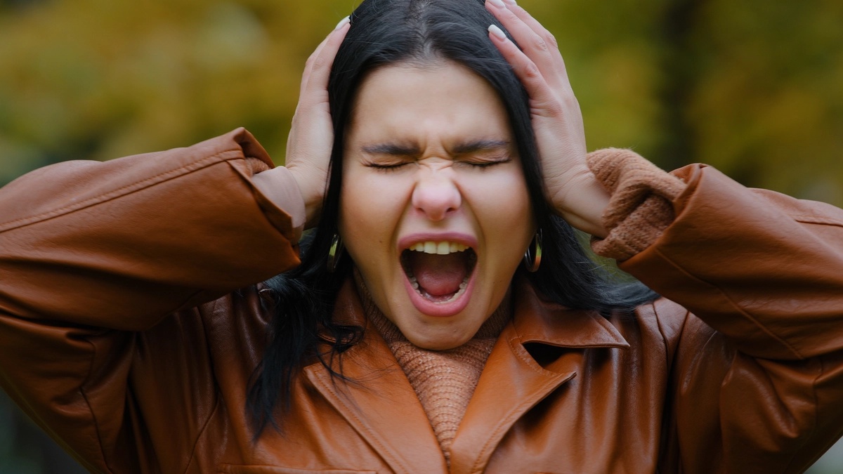 A woman holding her hands to her head with her mouth open.