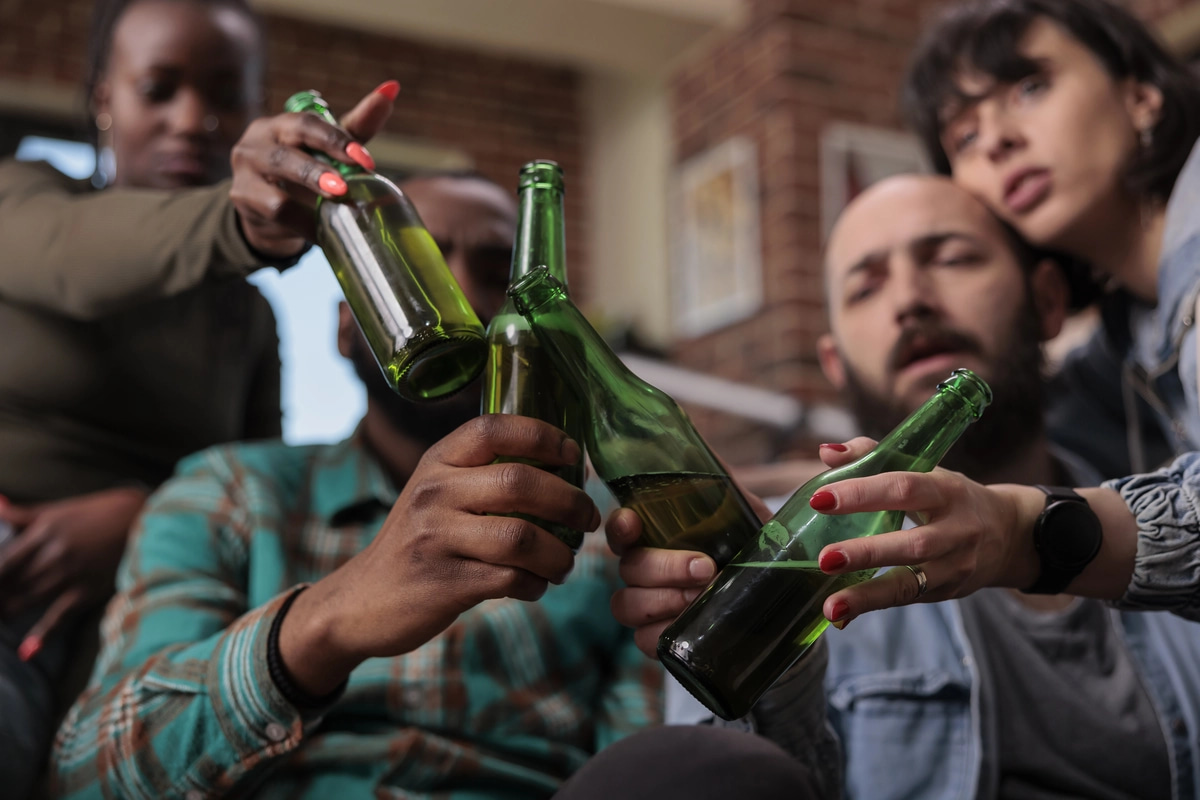 A group of friends drink beer, a sign of how alcohol addiction can develop.