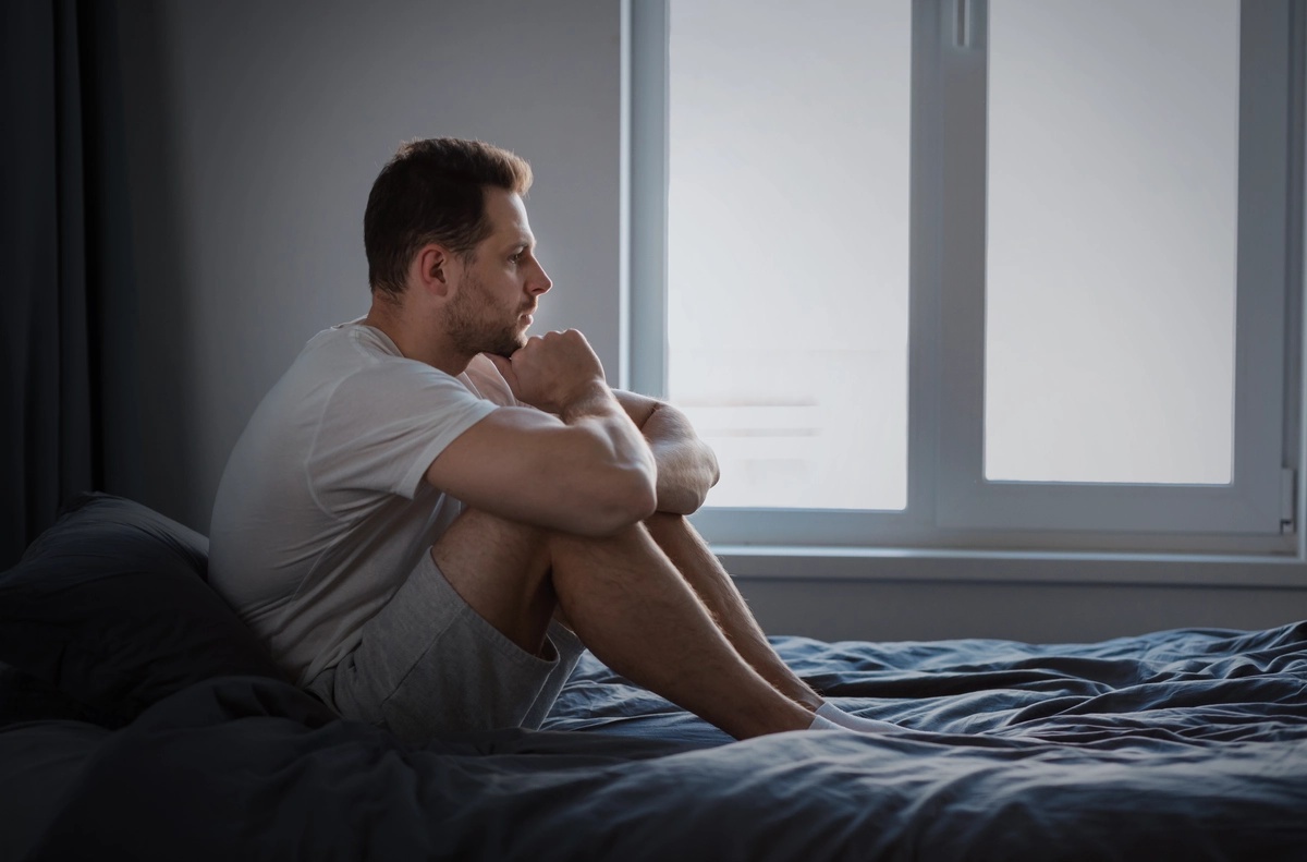 A man sitting on his bead with his knees to his chest