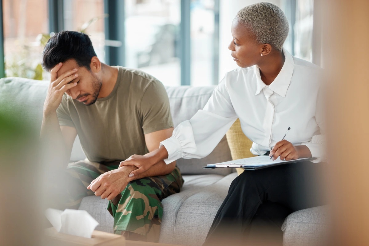 A therapist comforts her client as they sit together on a couch and discuss the possibility of outpatient rehab.