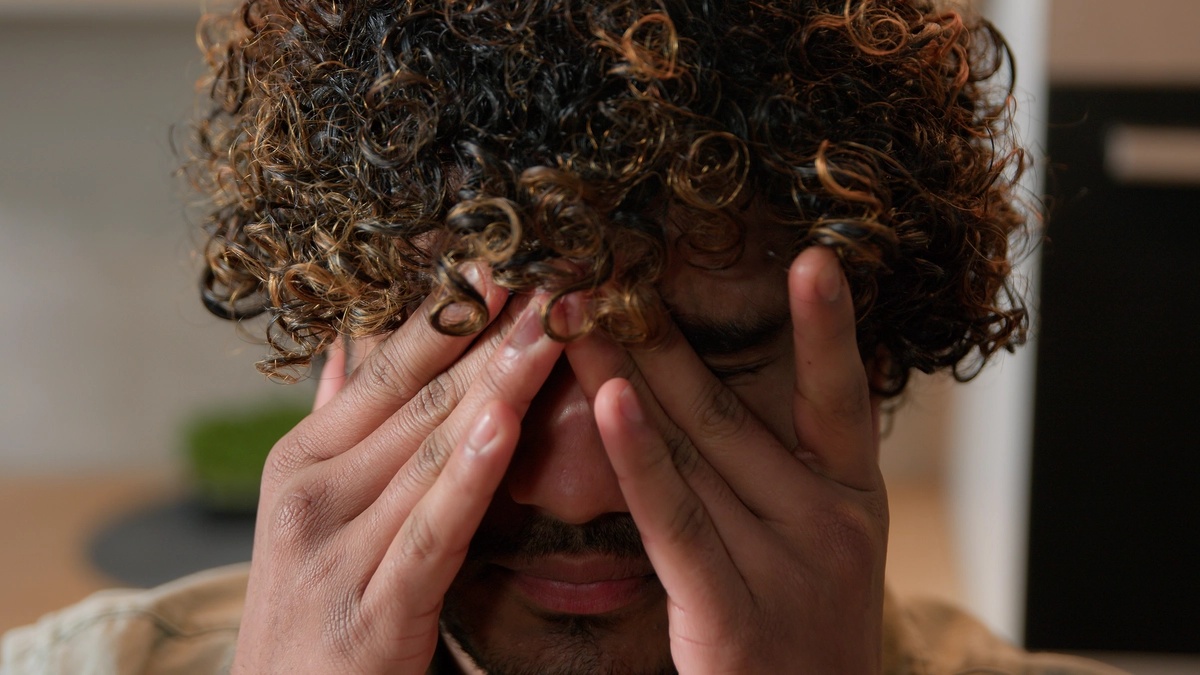 A man pressing his hands to his face.