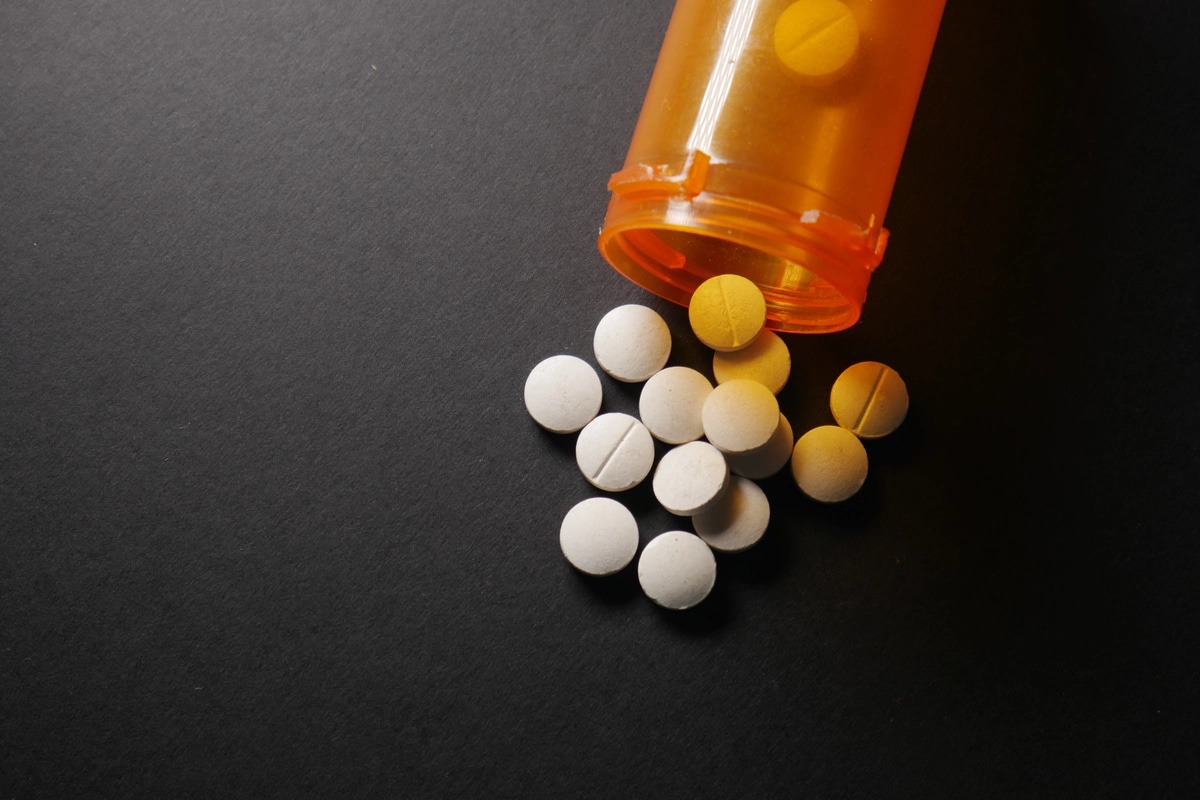 A bottle of prescription medication spilled onto a tabletop, a common sight during prescription drug addiction.