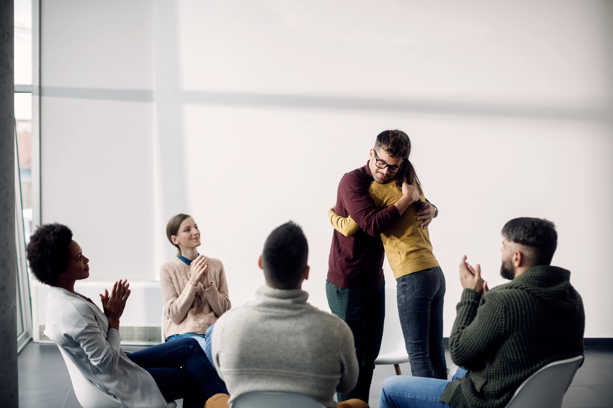 Two people hug at a group meeting for people dealing with alcohol addiction.