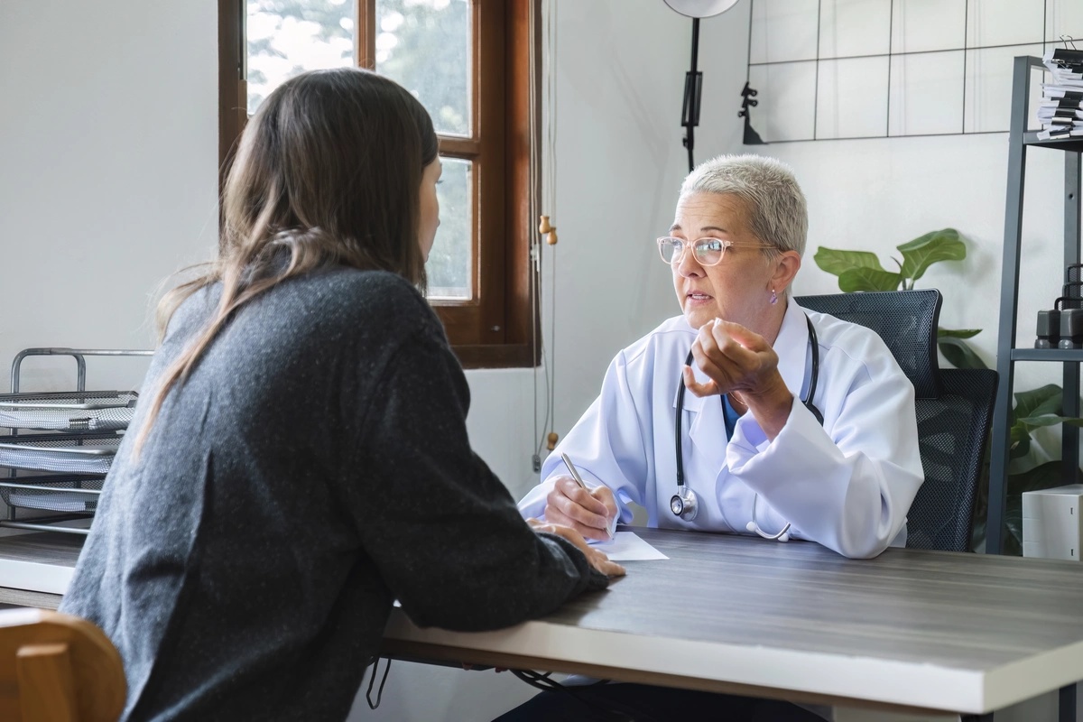 A drug rehab physician speaks to her patient across a table.