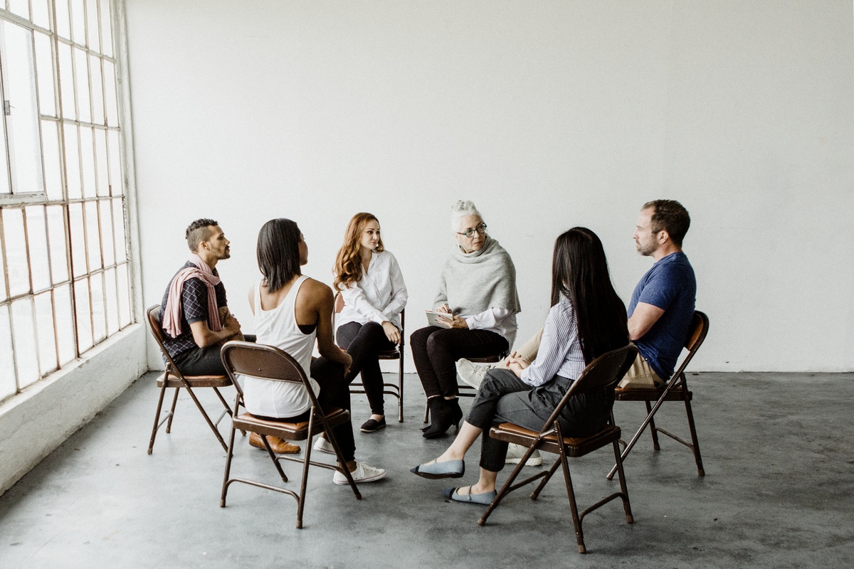 Multiple people sitting in on a group therapy session.