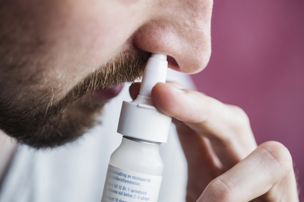 A man shooting nasal spray into his nostril, possibly struggling with inhalant addiction.