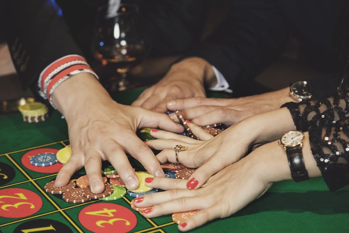 Multiple gamblers claiming their winnings at a roulette table, possibly suffering from gambling addiction.