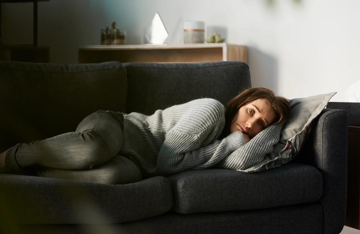 An unhappy woman lying on a couch.