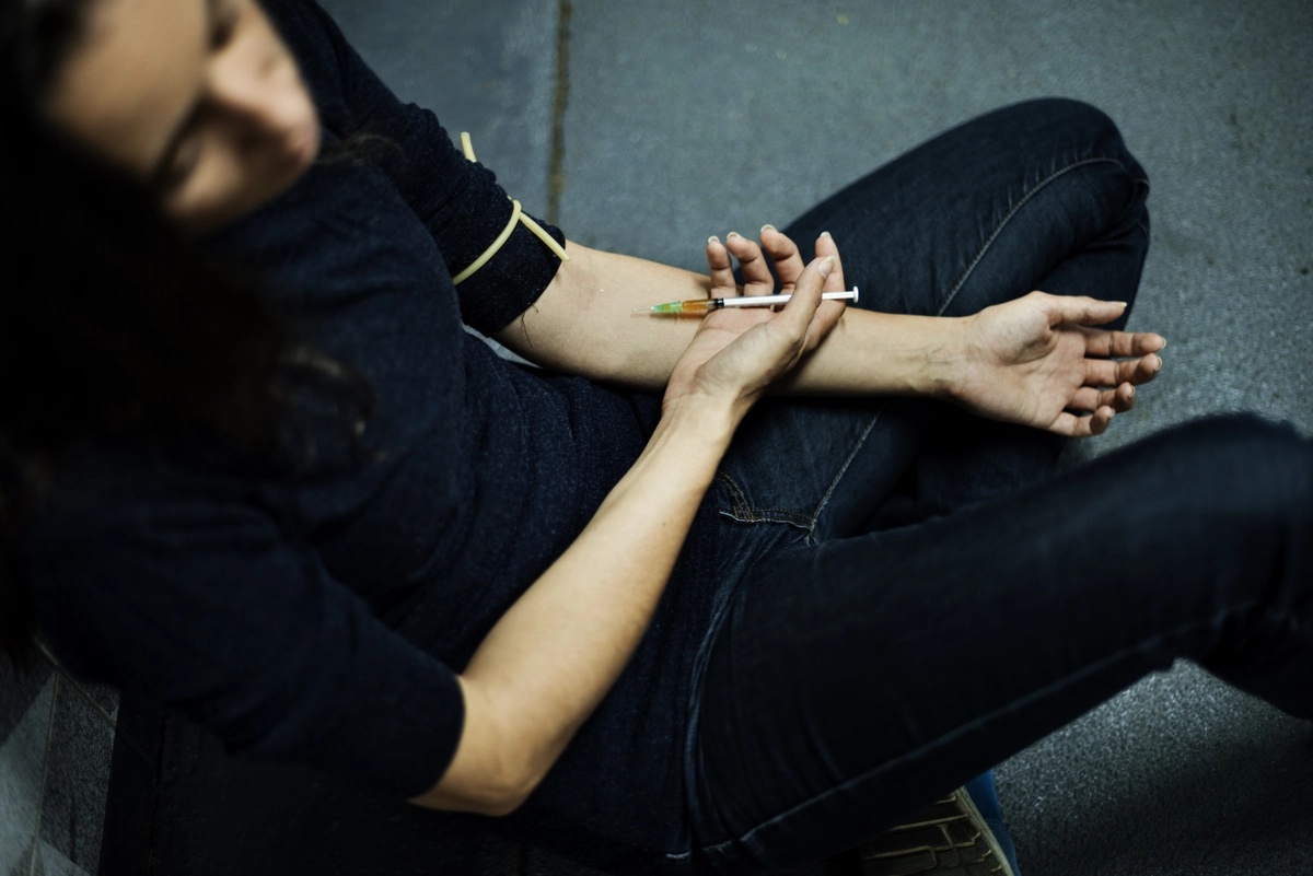 A person injecting an illicit stimulant into their forearm, a sign of stimulant addiction.