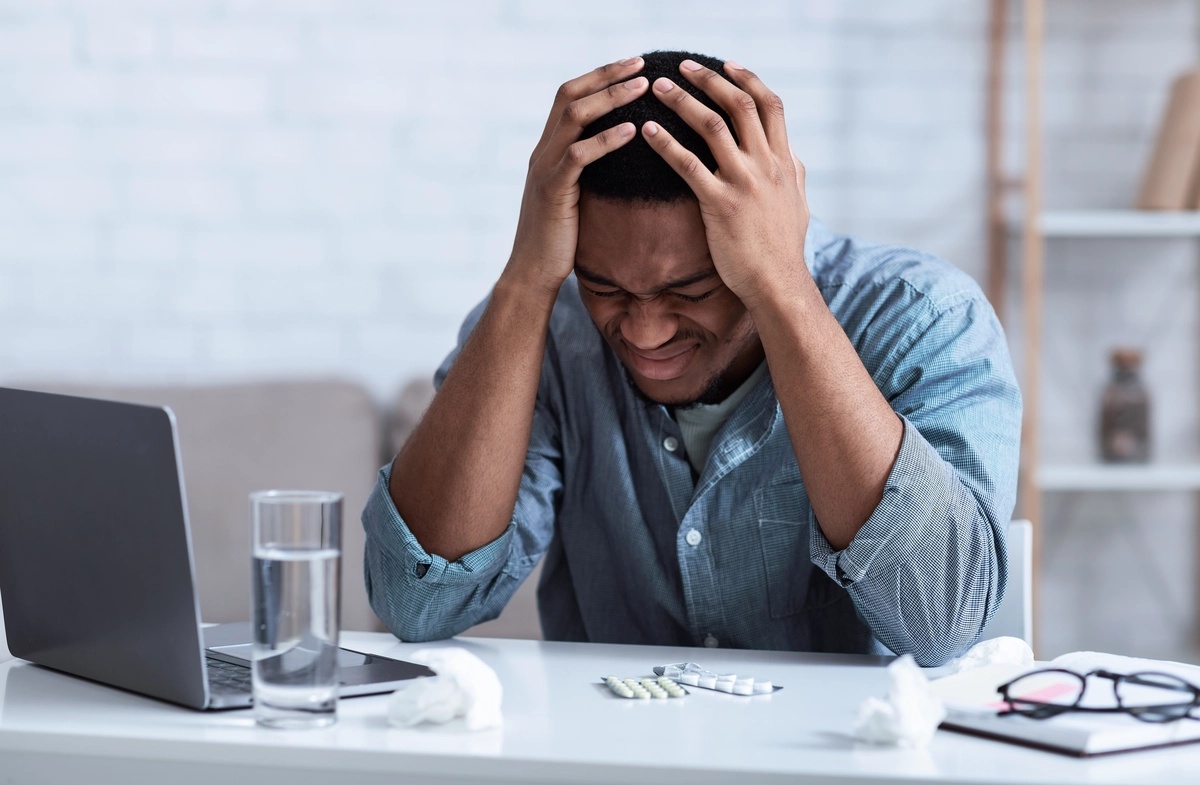 Man with cenesthopathic schizophrenia unhappy with unpleasant sensations holding his head in his hands.