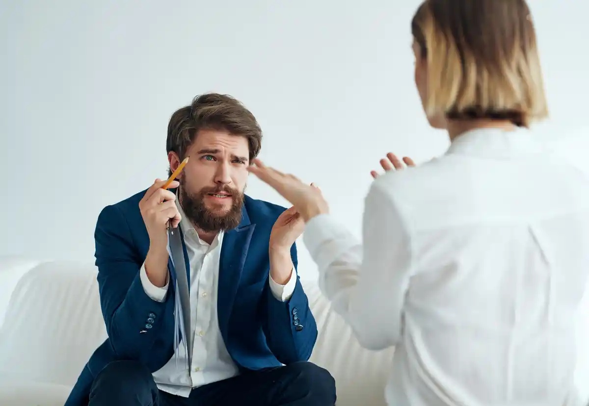 A man talks to his therapist while sitting on a couch.