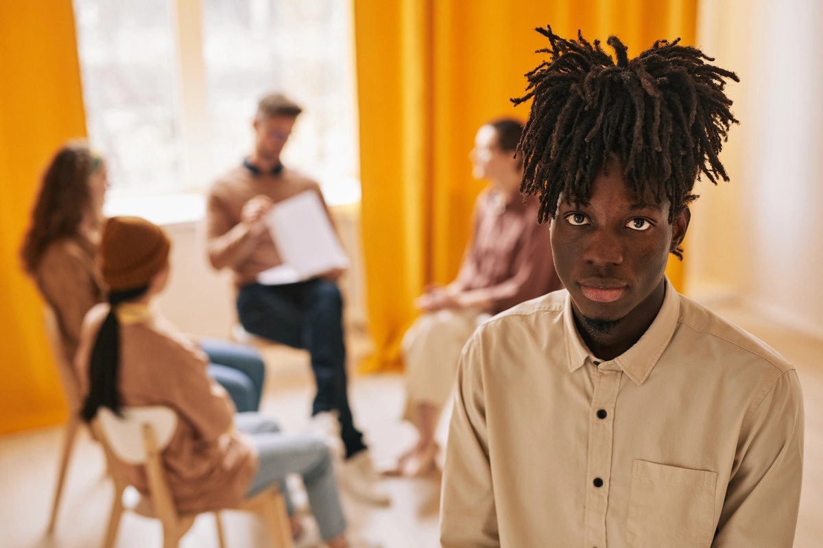 Group therapy session with one participant looking at the camera.