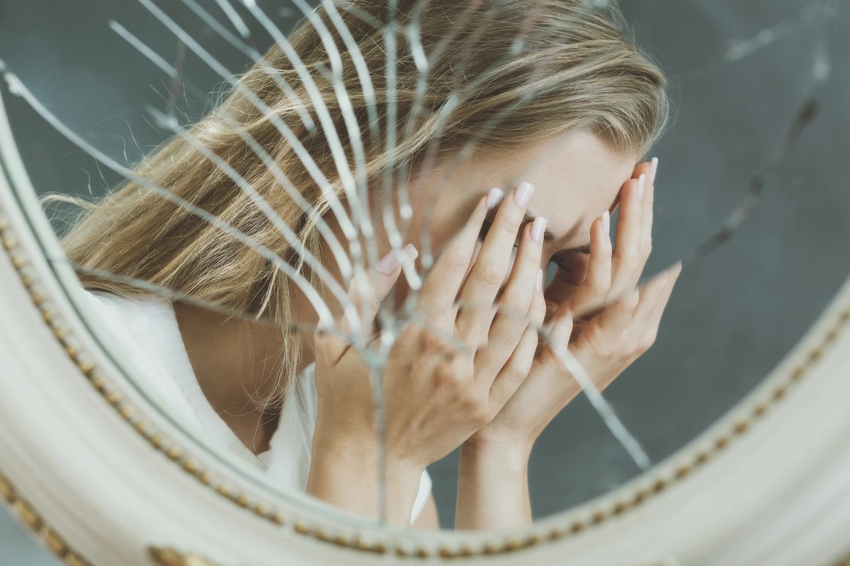 A woman's reflection in a broken mirror.