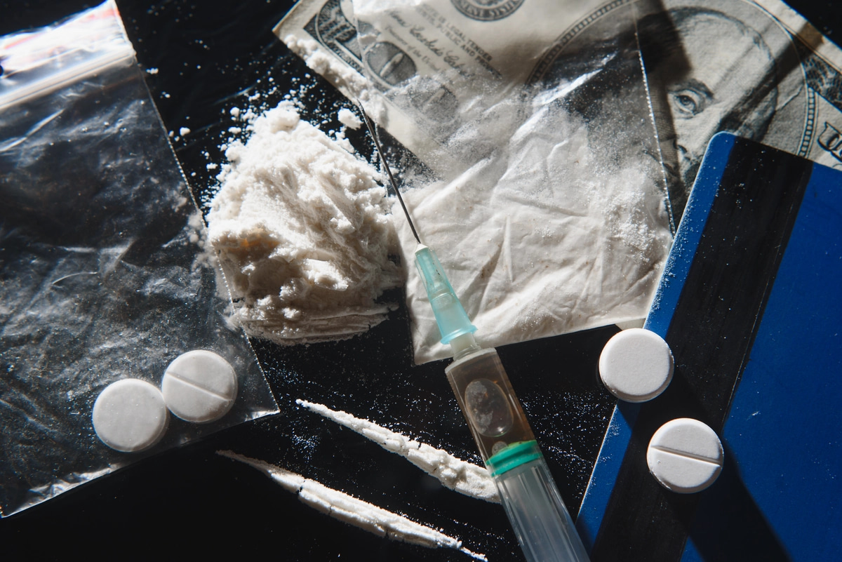 The signs of cocaine addiction: powder, needles, lines of cocaine, and pills.