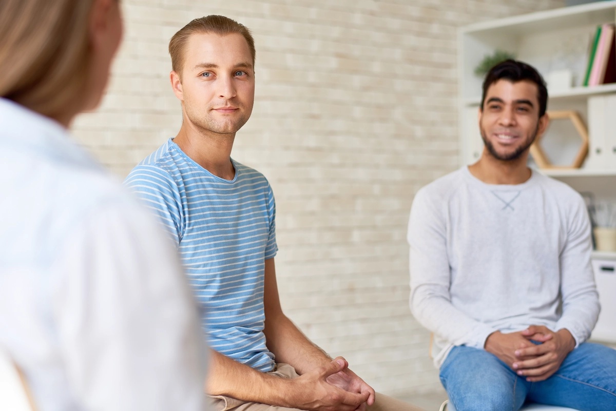 Treatment session for cenesthopathic schizophrenia in a group setting with smiling men at alternative therapy session.