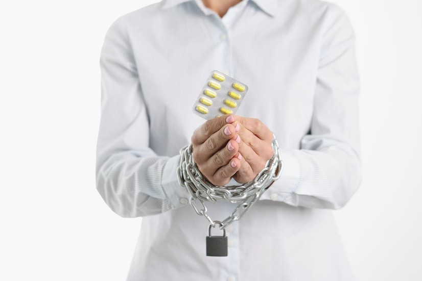 Handcuffed man holding a blister pack of pills.