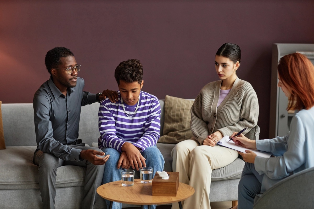 A family working through their issues with a therapist in a family therapy setting.