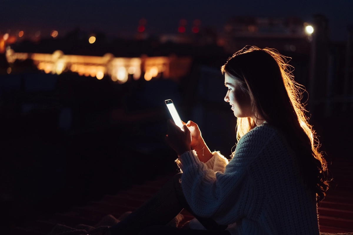 A woman with a phone addiction scrolling on her smartphone during a concert.