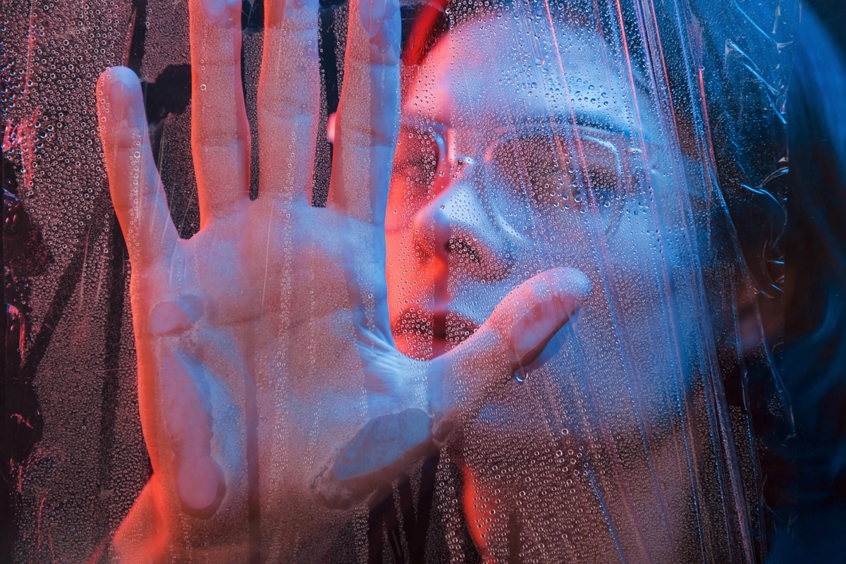 A woman pressing her hand up to a wet window.