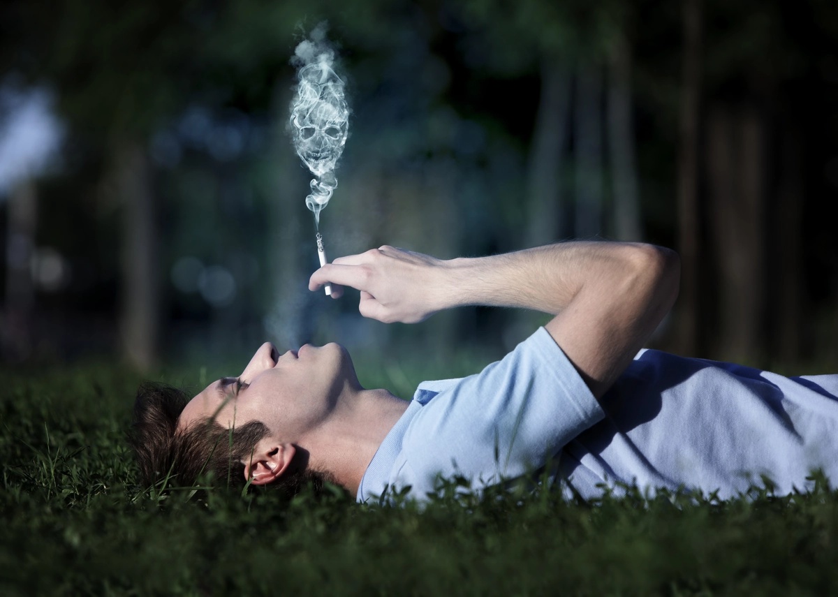 A man with marijuana addiction smokes weed outside while on his back. A man with marijuana addiction smokes weed outside while on his back.
