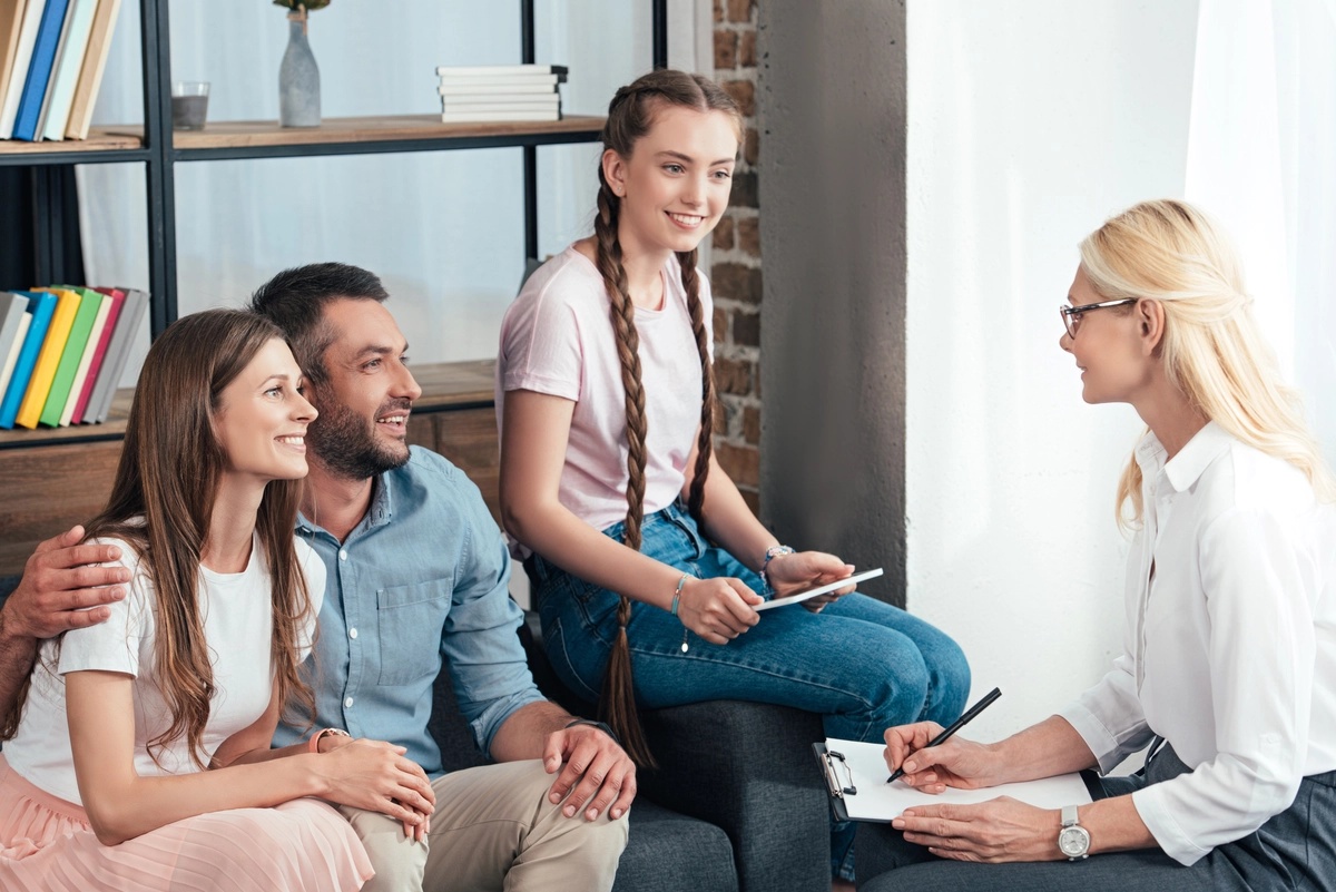 A family of three in a session with a therapist, in a family therapy setting. A family of three in a session with a therapist, in a family therapy setting.