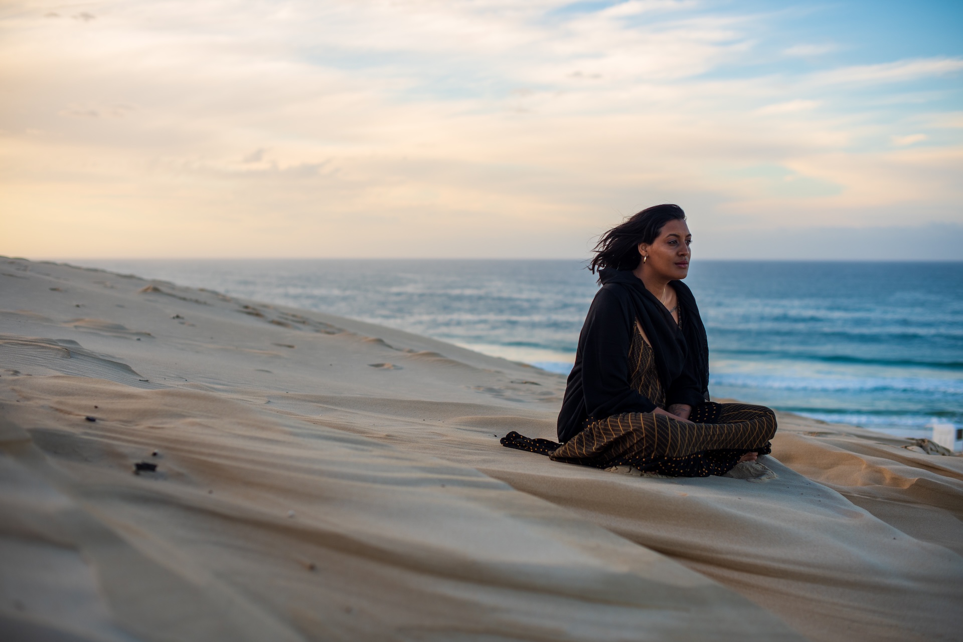woman-seen-sitting-on-sand-dune-while-watching-the-2025-01-07-09-49-25-utc (1)