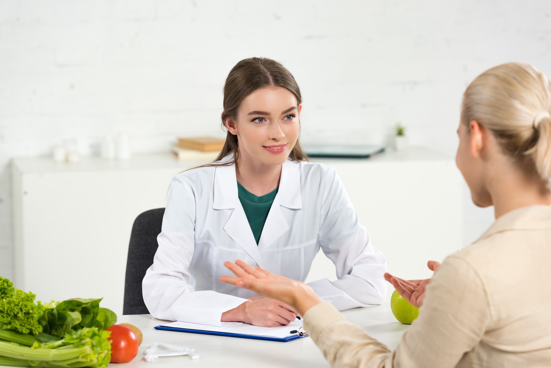 smiling-dietitian-in-white-coat-looking-at-patient-2024-11-19-01-00-07-utc