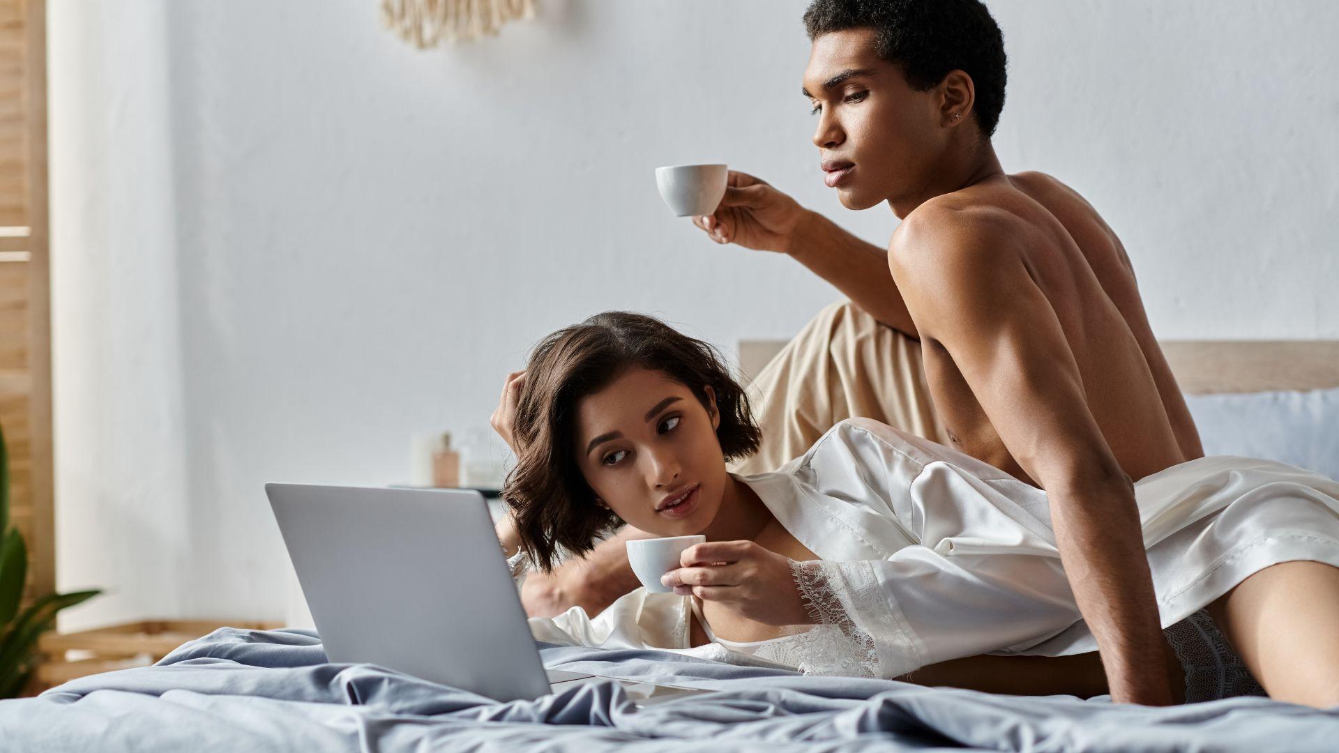 Porn addiction: man and woman in bed watching laptop.